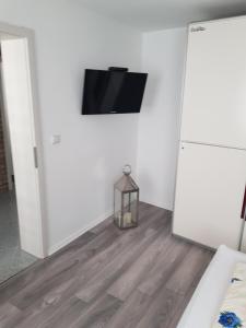 Habitación con TV en la pared y suelo de madera. en Inselblüte 2 en Werder