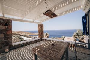 een veranda met een tafel en uitzicht op de oceaan bij Eternal Blue Kythnos in Mérikhas