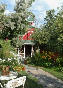 a red building with a clock tower in a garden at Le Mange Grenouille in Bic