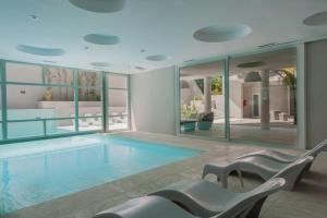 a large swimming pool with chairs in a building at Vizion Suites by D&G in Carilo