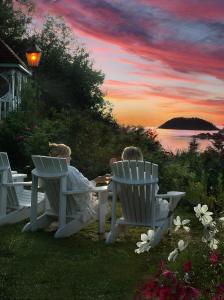 two children sitting in white chairs watching the sunset at Le Mange Grenouille in Bic