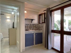 eine Küche mit blauen Schränken und eine Tür zu einer Terrasse in der Unterkunft Xenìa - Villa con Piscina Privata in Agrigento