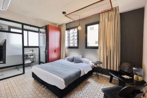 a bedroom with a bed and a tv and a chair at Levinski Market Hotel in Tel Aviv