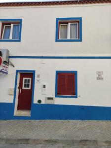 un edificio blu e bianco con porte e finestre rosse di Casa de Porto Covo Guest House a Porto Covo
