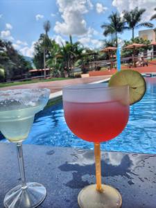 zwei Cocktails auf einem Tisch neben einem Pool in der Unterkunft Locação De Barracas EcoPark in São Pedro