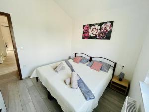 sypialnia z łóżkiem z białą pościelą i różowymi poduszkami w obiekcie Apartman Tina w mieście Murvica
