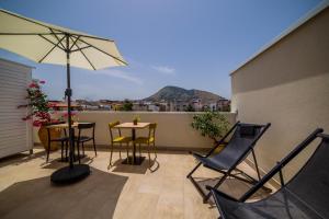 uma varanda com cadeiras e mesas e um guarda-sol em Ciuri' Affittacamere em Alcamo