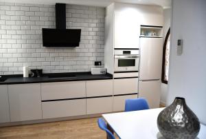a kitchen with white cabinets and a table and a tv at Casa VALOLI PLAYA MIRAMAR in Miramar