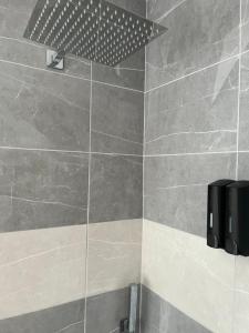 y baño con ducha de azulejos grises. en Terfyn Hall holiday Apartment 2, en Prestatyn