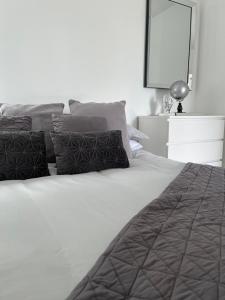 a white bed with two pillows and a mirror at Terfyn Hall holiday Apartment 2 in Prestatyn