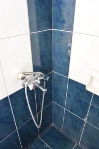 y baño con ducha con manguera y azulejos azules. en Hotel Hariklia en Agia Galini