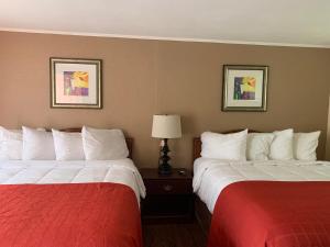 two beds in a hotel room with red and white sheets at Beachway Motel in Salisbury
