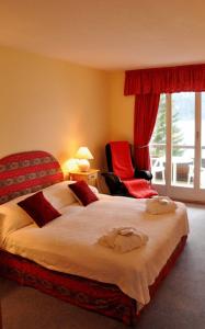 a bedroom with a large bed and a red chair at Seehotel Bären in Brienz