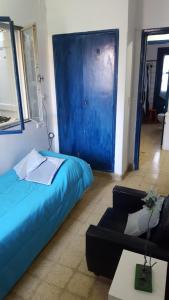 Una puerta azul en una habitación con cama y sofá en Hostel Cultural Casa Taller en Bahía Blanca