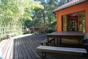 um deque de madeira com uma mesa e bancos sobre ele em Pousada Estância Rio Acima em Itamonte