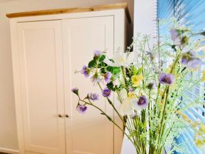 a vase filled with flowers in front of a cabinet at Grassington Cottage in Grassington