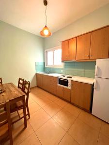 a kitchen with wooden cabinets and a table and a refrigerator at Grand Pension in Néa Koróni