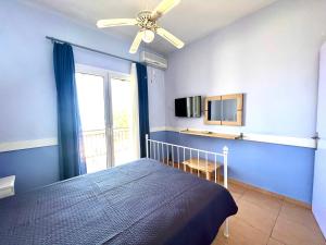 a bedroom with a bed with a ceiling fan and a window at Grand Pension in Néa Koróni