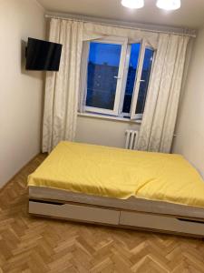 ein Schlafzimmer mit einem Bett mit einer gelben Decke darauf in der Unterkunft Apartament Roma in Danzig