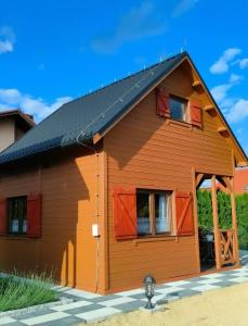 ein Holzhaus mit roten Fenstern und einem schwarzen Dach in der Unterkunft Domki Na Winnicy Zator Przeciszów in Przeciszów