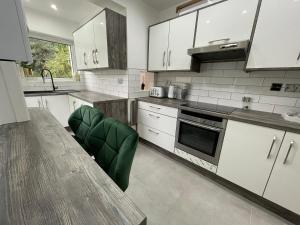 a kitchen with white cabinets and a table and green chairs at Orchid House in Birmingham