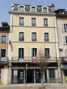 un gran edificio amarillo con ventanas en una calle en Tulle : bel appartement lumineux en centre ville en Tulle