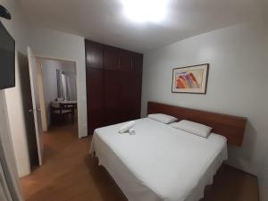 a bedroom with a white bed and a table at Apartamentos La Residence in Goiânia