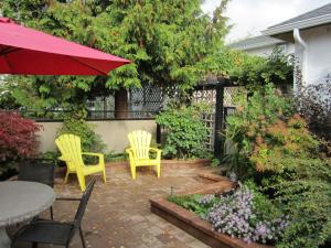 eine Terrasse mit 2 Stühlen und einem Tisch mit einem Sonnenschirm in der Unterkunft Heathergate Cottage and Suites in Victoria