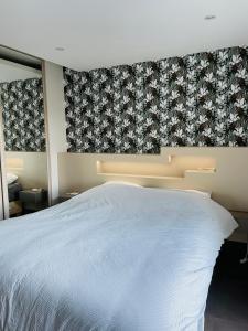 1 dormitorio con cama blanca y papel pintado con motivos florales en Maison des Coteaux blancs, en Chaudefonds-sur-Layon