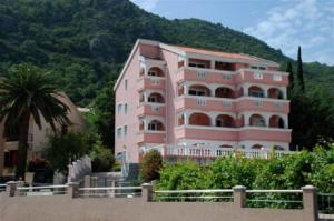 a pink building in front of a mountain at Vila Tamara Apartmani in Bečići