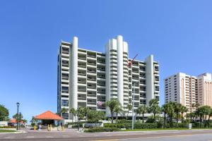 a tall white building with palm trees in front of it at 1506 Lighthouse Towers in Clearwater Beach
