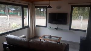 a living room with a couch and a tv and windows at Escallonia House in San Martín de los Andes