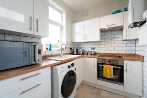 cocina con armarios blancos, lavadora y secadora en Spacious & Homely, 4 BR, Parking, Close to Centre, en Sheffield