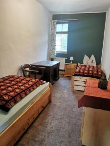 - une chambre avec 2 lits, un bureau et une table dans l'établissement Ruhige Ferienwohnung im Gutshaus, à Niederorschel