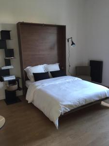 a bedroom with a large white bed with a wooden headboard at Studios Régina (Mer-Golf) in Biarritz