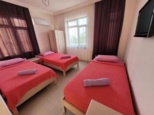 Habitación con 2 camas con sábanas rojas y TV de pantalla plana. en Cetin Pansiyon, en Fethiye