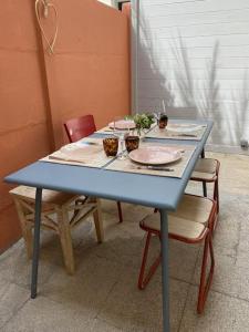 een blauwe tafel met twee stoelen en een tafel met borden bij Maison cosy, wifi terrasse, proche plage, gare, centre in Arcachon
