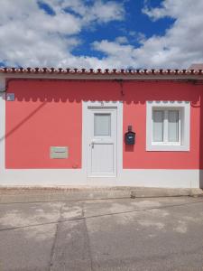 a red and white building with a white door and windows at Casa Coral in São Marcos do Campo