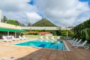 Ein Swimmingpool mit Liegestühlen und ein Hügel im Hintergrund in der Unterkunft VOA Hotel União in Caxambu