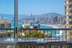 a balcony with chairs and a view of a city at La Perla Benidorm Apartment seaview & pool Levante Beach in Benidorm