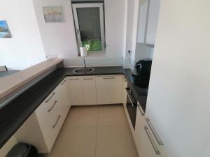 a small white kitchen with a sink and a window at Apartman Sara in Pržno +3 photos