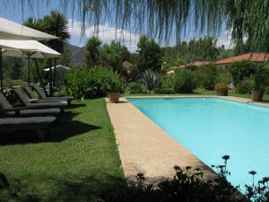 a swimming pool in a yard with chairs and an umbrella at Mapuyampay Lodge Gastronómico in Santa Cruz