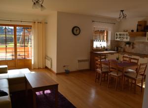 a living room with a table and a kitchen at Apartament Rysulówka 180 in Kościelisko
