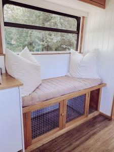 Levaré的住宿－Relaxing retreat for 2 on beautiful converted bus，靠窗前的带枕头的长凳