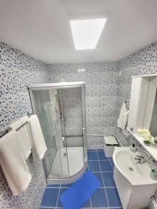 y baño de azulejos azules con ducha y lavamanos. en Amaraz Center, en Sibiu