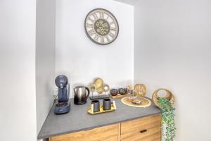 - un comptoir de cuisine avec divers appareils et une horloge dans l'établissement Charmant studio au pied du métro (ligne 8), à Créteil
