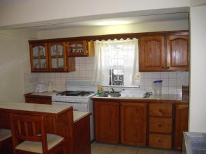a kitchen with wooden cabinets and a stove top oven at JerryDon's Apartment in Saint Georgeʼs
