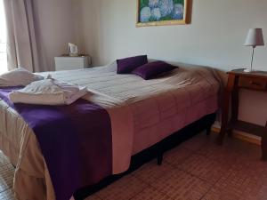 1 dormitorio con 1 cama grande con sábanas moradas en Posada Miralejos en Trapiche
