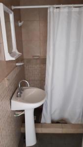 baño con lavabo y cortina de ducha blanca en Posada Miralejos en Trapiche