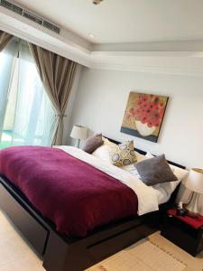 a bedroom with a large bed with a purple blanket at Luxury 2 bedroom Apt in The Pearl with Marina view in Doha